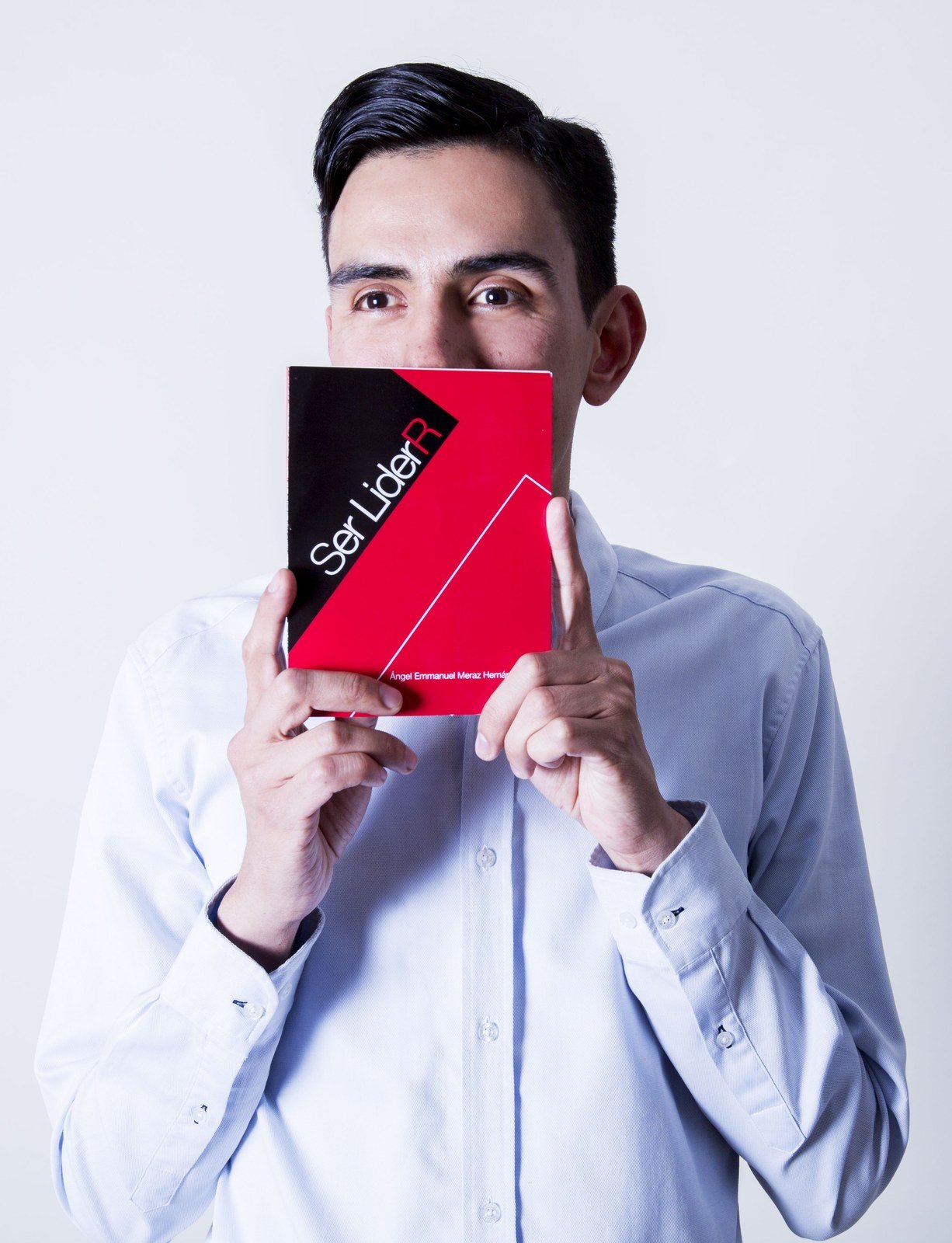 Emmanuel Meraz sosteniendo su libro Ser LiderR frente a su rostro