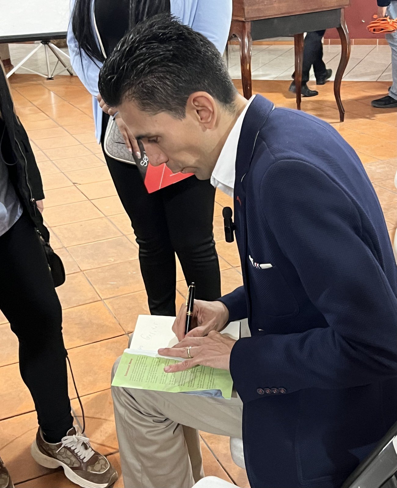 Emmanuel Meraz firmando un ejemplar de su libro para una persona en un evento