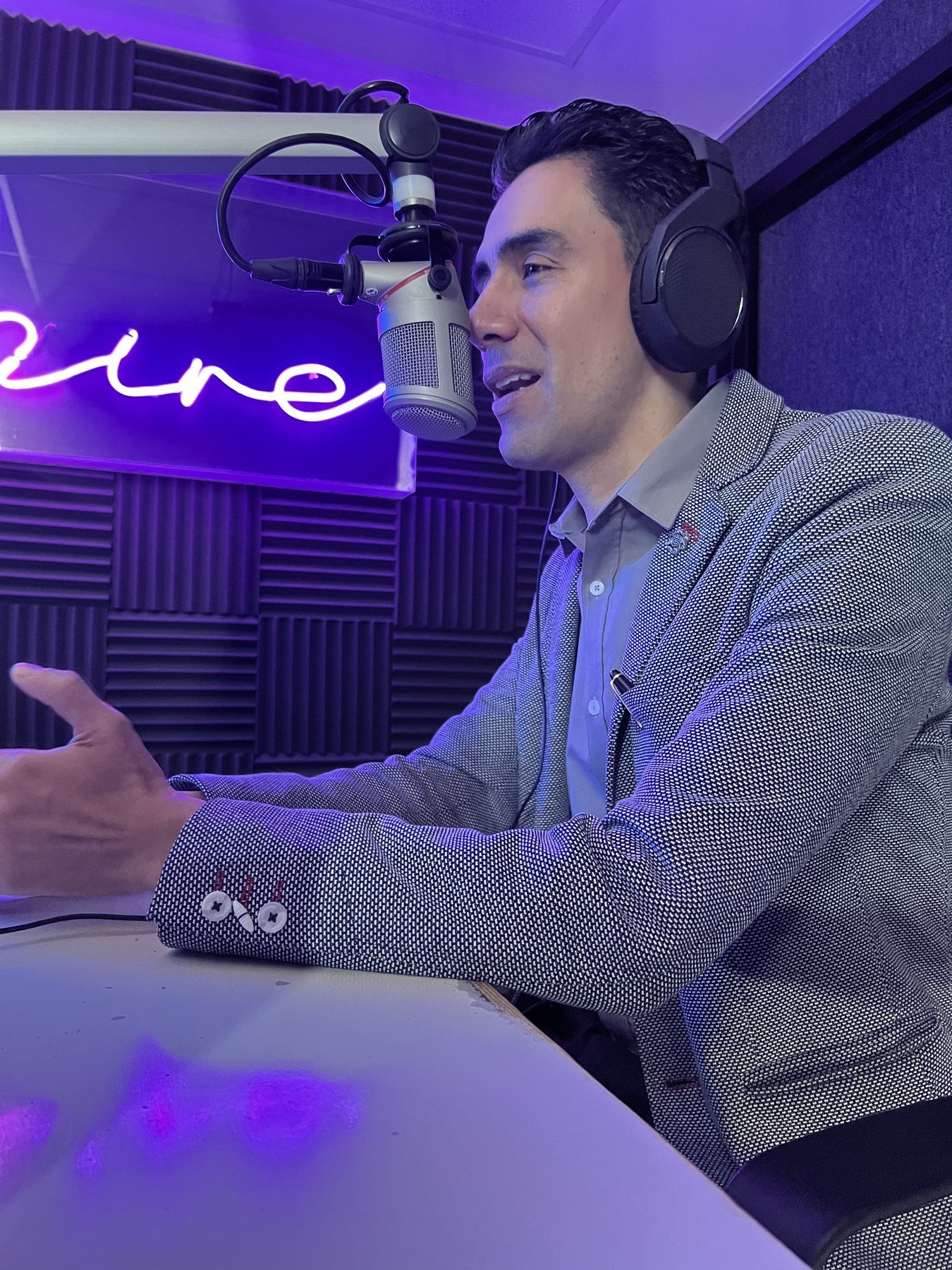 Emmanuel Meraz con audífonos, hablando frente a un micrófono, en un estudio de podcast