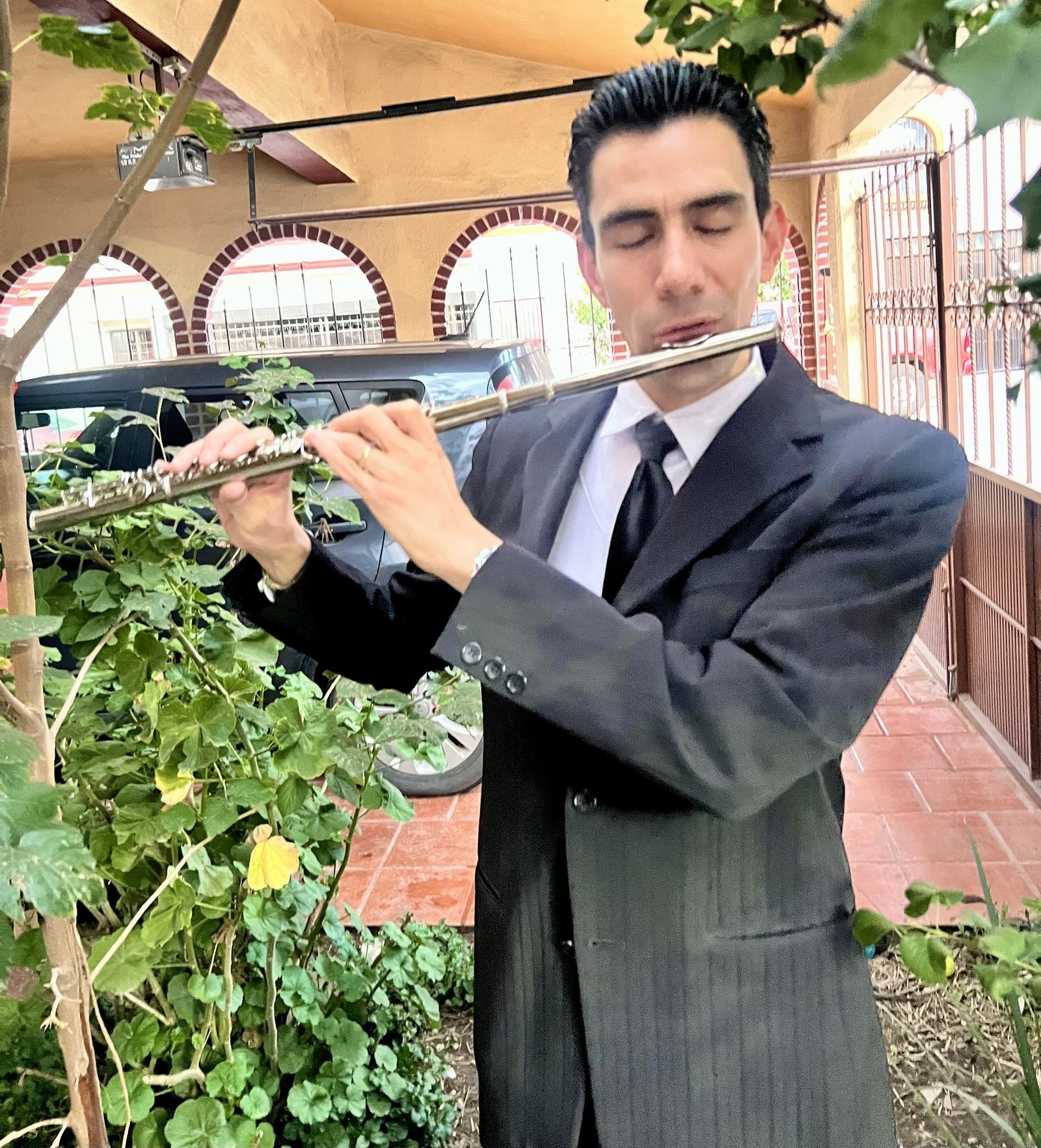 Emmanuel Meraz tocando la flauta transversal en un patio con plantas