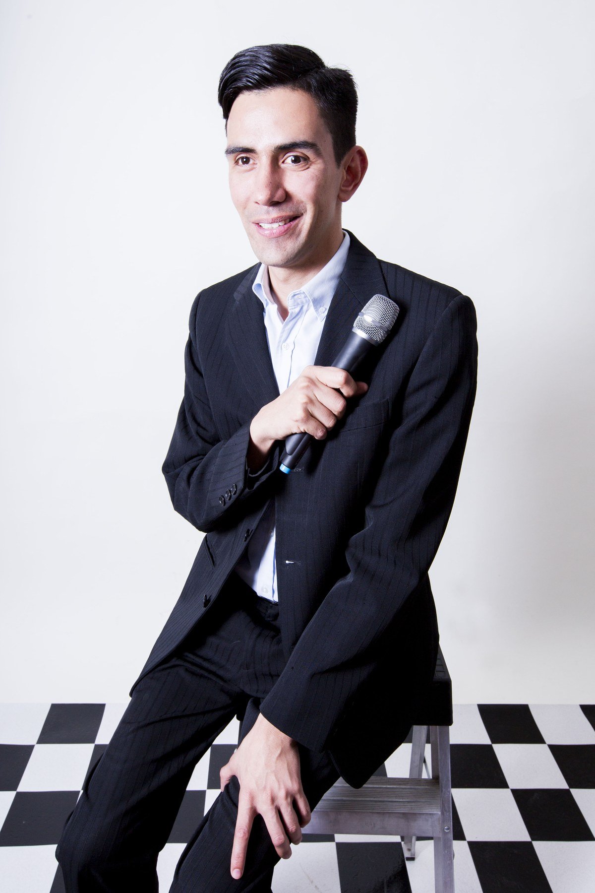 Emmanuel Meraz sentado, sonriendo, con un micrófono en la mano